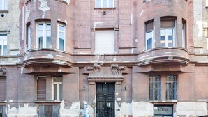 Un edificio storico con un ingresso nero e decorato, diverse finestre e un numero civico ben visibile.