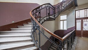 A spiral staircase with ornate metal railings and a wooden handrail, leading to an upper floor. - Central Luxury Apartment (Budapest)