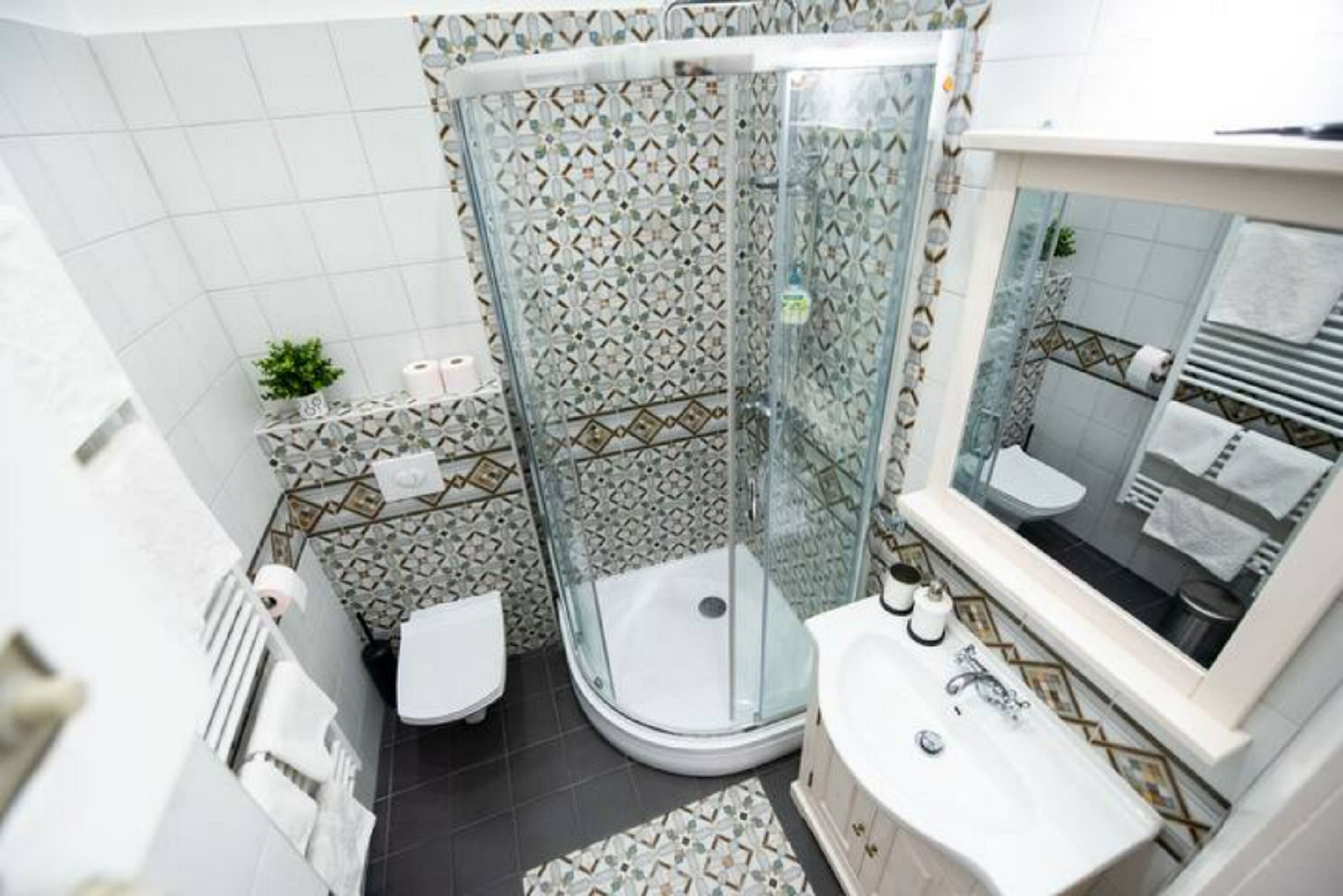A modern bathroom with a glass shower enclosure, a white toilet, and a sink with a mirror.