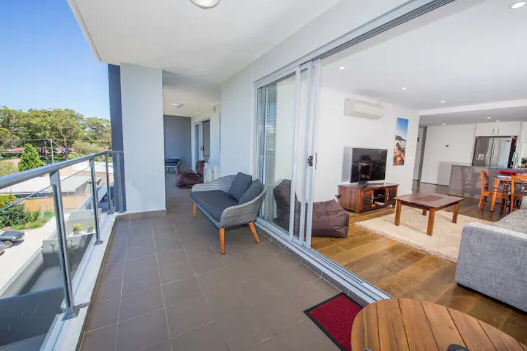 Un appartement moderne doté d’un balcon, d’un espace de vie avec un canapé et une télévision, et d’une cuisine.