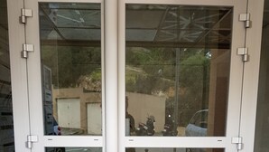 Un insieme di porte in vetro con cornice metallica, che si apre su un patio piastrellato.