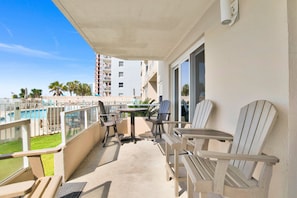 A balcony with a pool view, outdoor seating, and a building in the background.