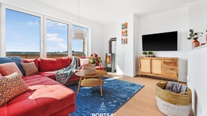 Een moderne woonkamer met een rode bank, een houten salontafel en een groot raam.