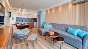 Una sala de estar moderna con un sofá gris, un sillón mecedor y una mesa de comedor.