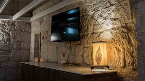 Ein Innenraum mit einer Steinsäule, einem angebrachten Fernseher, einer Holzauskładung und einer Wanduhr.