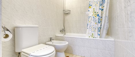 A bathroom with a toilet, bidet, and bathtub.