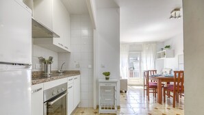 Eine Küche mit weißen Schränken, einer Granitabdeckung, einem Herd und einem Spülbecken. Es gibt einen Essbereich mit Holzsesseln und einem Tisch.