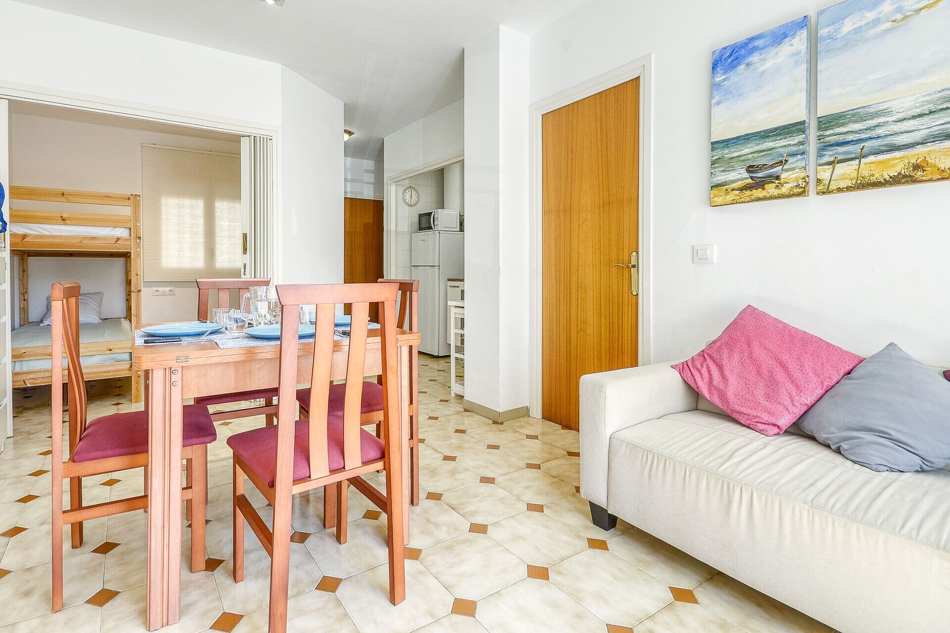 A compact living space with a dining area, kitchenette, and a sofa with cushions.