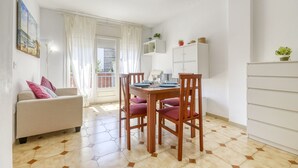 Ein kompakter Wohnbereich mit Essplatz, einer Couch, einem Schrank und einem Balkon mit Blick.