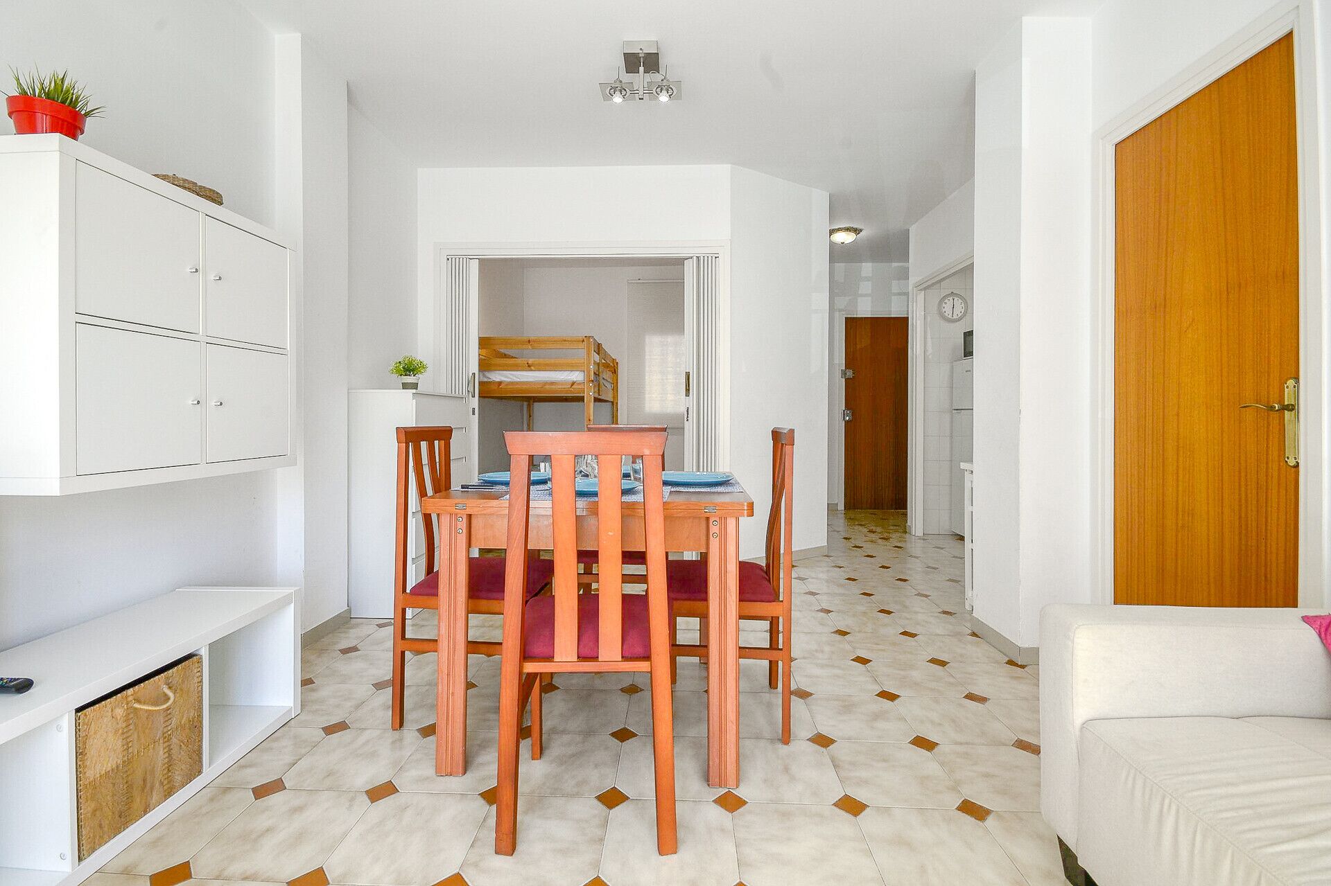 Un espace de vie compact comprenant un coin repas, un lit superposé et une kitchenette.