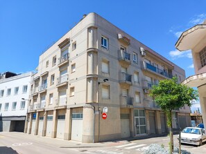 Un edificio de varios pisos con balcones, una señal de 'prohibido el paso' y un coche estacionado.