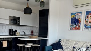 Een moderne keuken met een centraal eiland, barstoelen en een blauwe bank in een woonruimte.