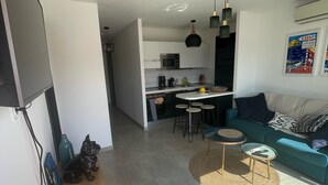 Een moderne woonkamer met een bank, salontafel en een eetgedeelte, met een keuken op de achtergrond.