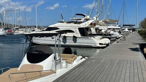 Een jachthaven met verschillende jachten, een houten looppad en een heldere blauwe lucht.