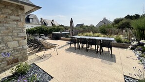 A patio with a table and chairs, surrounded by stone walls and plants.