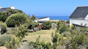 A coastal residential area with houses, a grassy yard, and a view of the sea.
