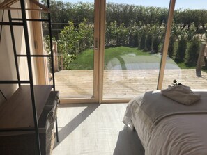 Une chambre avec une grande fenêtre, un lit et un banc en bois.