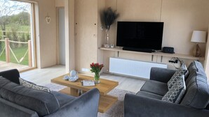 Ein modernes Wohnzimmer mit einer Sofagarnitur, einem Couchtisch mit Blumenvase, einem Flachbildfernseher und einer Heizung.