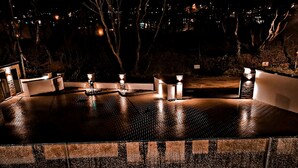 A wet outdoor dining area with a brick floor, white tables, and candles. - Oceanwalk - sleeps 8 guests  in 4 bedrooms (Perranporth)