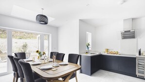 A modern kitchen with a central island, dark cabinetry, and a large window providing natural light. - Oceanwalk - sleeps 8 guests  in 4 bedrooms (Perranporth)