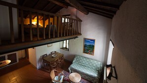 Una habitación rústica con una escalera de madera, una mesa de comedor con sillas, un sofá y un cuadro en la pared.
