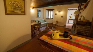 Una habitación acogedora con techo de madera, un comedor con mesa y sillas, un sofá y una chimenea.