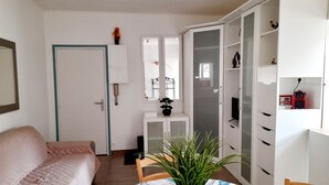 A room with a bed, a small table with a plant, a TV, and a wardrobe.