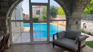 Ein Zimmer mit Steinwand, großem Fenster mit Blick auf einen Swimmingpool und einer gepolsterten Bank.