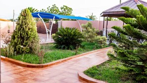 Ein Gartenbereich mit einem gewundenen Weg, einer blauen Markise und einem Gazebo.