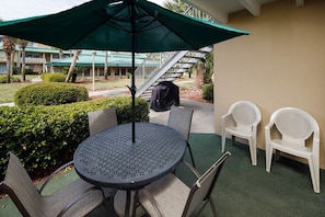 An outdoor seating area with a round table, two chairs, and a large umbrella.