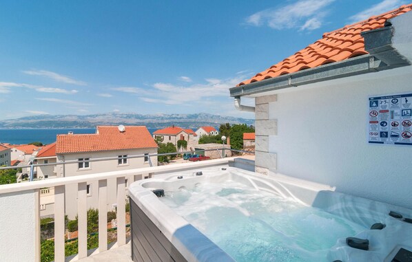 Une terrasse sur le toit avec un jacuzzi, une vue sur la mer et un panneau indiquant les consignes de sécurité pour le spa.
