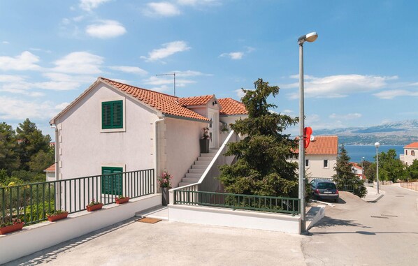 A two-story building with a red-tiled roof, a staircase leading to the upper floor, and a view of the sea in the background. - Nice apartment in Supetar with WiFi (Supetar)