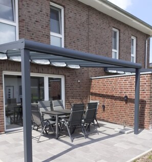 A patio with a table and chairs under a pergola.