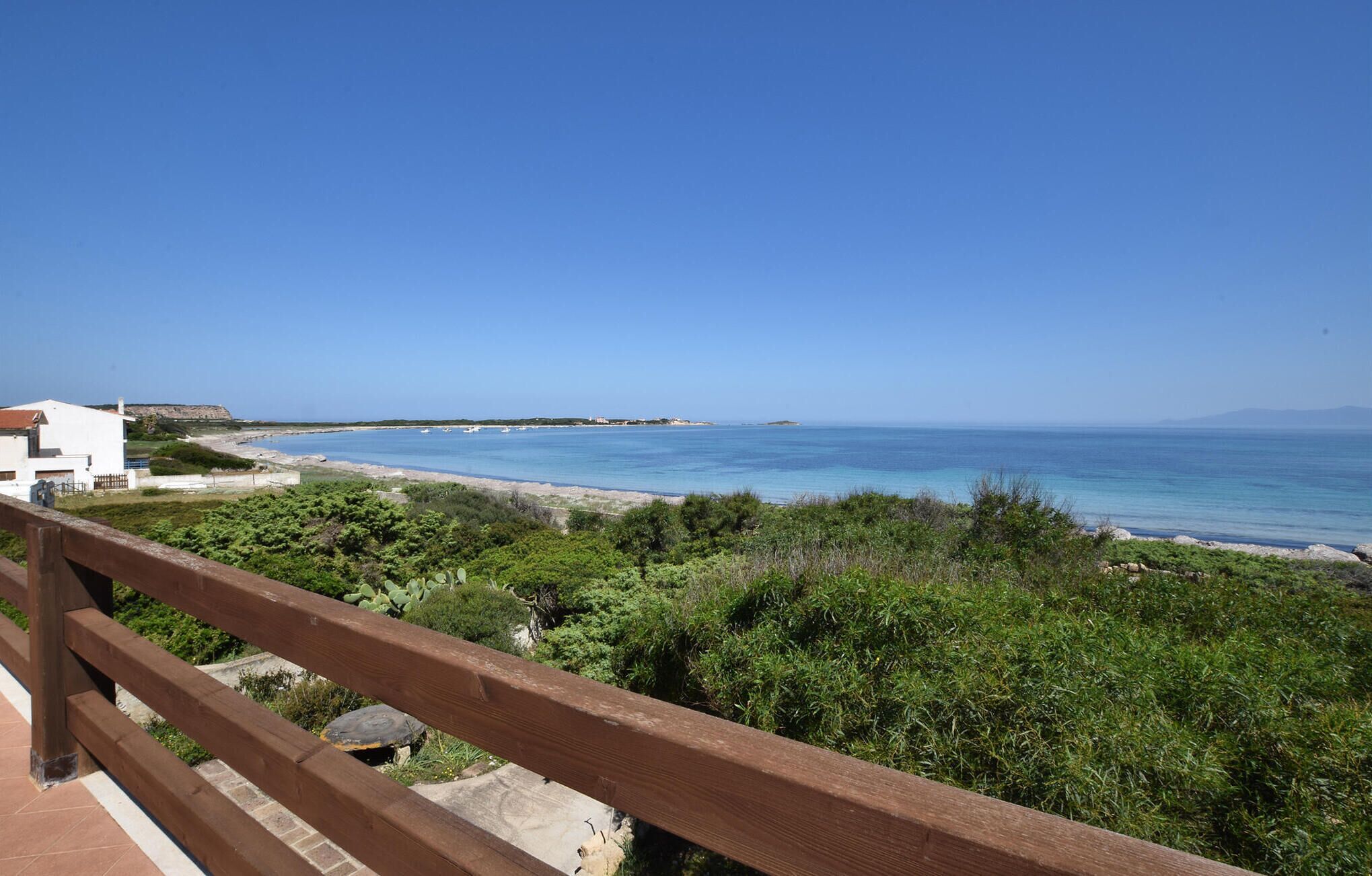 Blick auf die Küste mit einem Holzbalkon, der auf einen Strand und das Meer blickt.