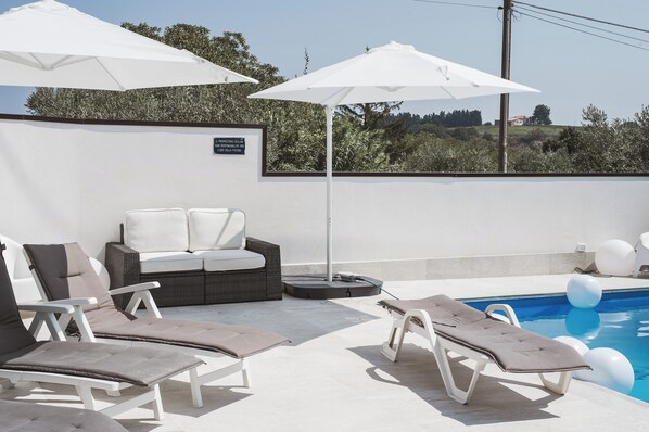 A poolside area with lounge chairs, a sofa, and umbrellas. - ROME - Spacious apartment in a villa with a pool and barbecue, 1 km from the sea (Riccio)