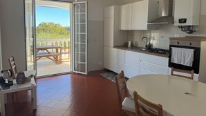Uma cozinha com armários brancos, fogão a gás e um espaço de jantar com mesa e cadeiras.