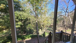 A view from a window overlooking a garden with a wooden deck and a variety of trees. - Riverside Getaway - Enjoy Quiet Life Right on the Duck River (Shelbyville)