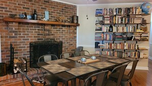 A dining area with a brick fireplace, a bookshelf, and a ceiling fan. - Riverside Getaway - Enjoy Quiet Life Right on the Duck River (Shelbyville)