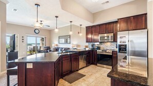 A spacious kitchen with dark wood cabinets, stainless steel appliances, and a large island. - Beautiful Walk-in Lake View Condo with HA Features • Sunroom + Covered Patio (Branson)