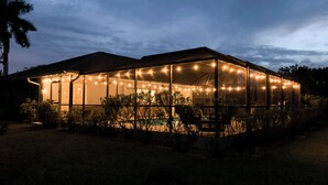 Uma casa grande e moderna com fachada de vidro e luzes de cordão.