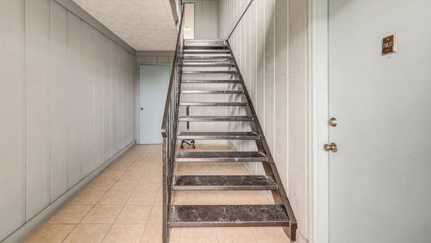 A narrow hallway with a metal staircase leading to a door with a brass doorknob. - < Half-Mi to Fort Clinch Beach! Condo w/ Balcony (Fernandina Beach)