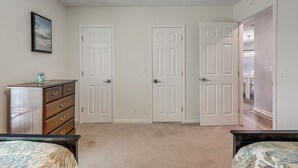 A bedroom with two doors, a dresser, a bed, and a hallway leading to another room. - < Half-Mi to Fort Clinch Beach! Condo w/ Balcony (Fernandina Beach)