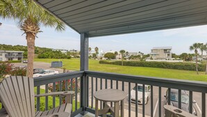 A covered outdoor area with a table and chairs, overlooking a residential neighborhood with houses and palm trees. - < Half-Mi to Fort Clinch Beach! Condo w/ Balcony (Fernandina Beach)