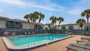 A rectangular swimming pool with a tiled edge, surrounded by lounge chairs and a brick patio. - < Half-Mi to Fort Clinch Beach! Condo w/ Balcony (Fernandina Beach)