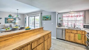 Eine moderne Küche mit Holzschnitzereien, einer zentralen Kochinsel und einem großen Fenster mit dekorativer Gardine.