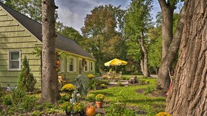 A house with a garden, a yellow umbrella, and a patio with outdoor furniture. - Pittsford ‘Trolley Home’ - Near Erie Canal! (Pittsford)