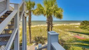 A view from a balcony overlooking a beach with palm trees and a clear blue sky. - Luxe Beachfront WindMark Cottage w/ Deck! (Port St. Joe)