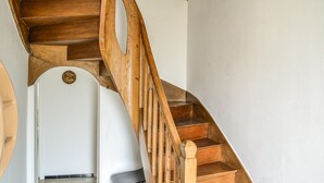 En trappe i træ med et svunget design, der fører op til en hvid dør med en dekorativ plade.