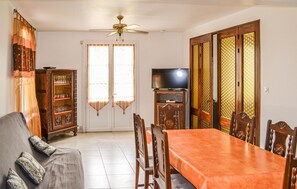 A dining area with a wooden table and chairs, a sofa, a television on a stand, and a cabinet with glassware. - Awesome home in Coutras with WiFi (Coutras)