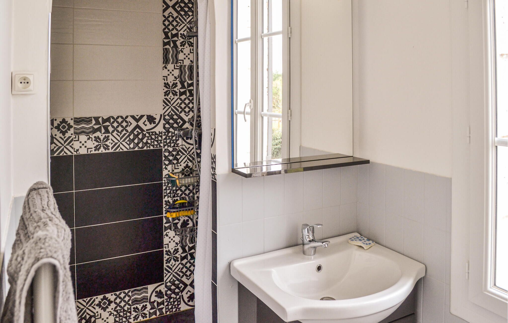 A bathroom with a white sink, a mirror, and patterned tiles.
